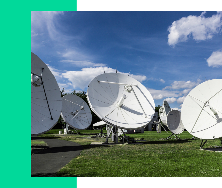 A group of satellite dishes sitting on top of a green field.