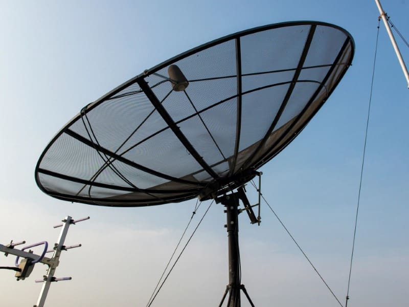 A satellite dish sitting on top of a metal pole.