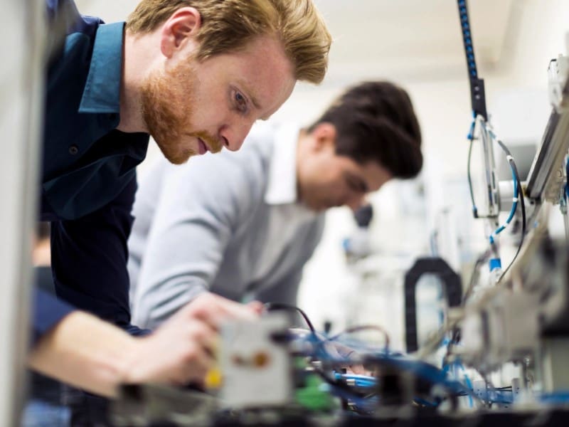 Two men working on electronics in a lab.