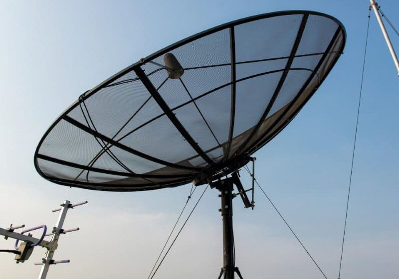 A satellite dish sitting on top of a metal pole.